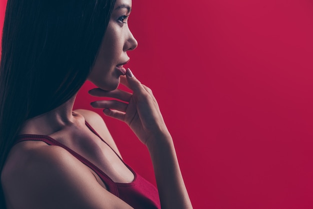 Elegant woman in red dress posing against the red wall