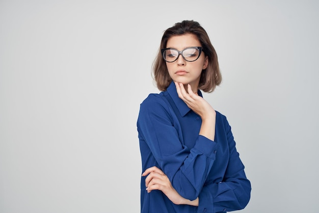 Elegant woman with glasses in blue shirt fashion light background