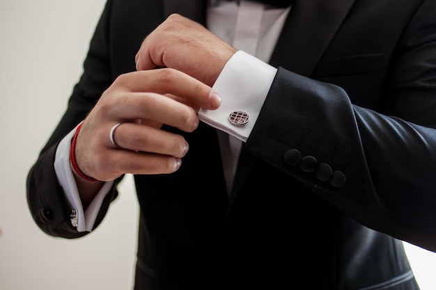 Elegant young fashion man looking at his cufflinks while fixing them. groom is ready for wedding