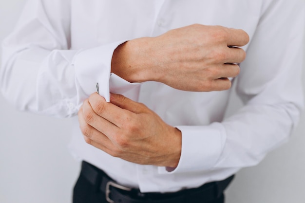 Elegant young fashion man looking at his cufflinks while fixing them