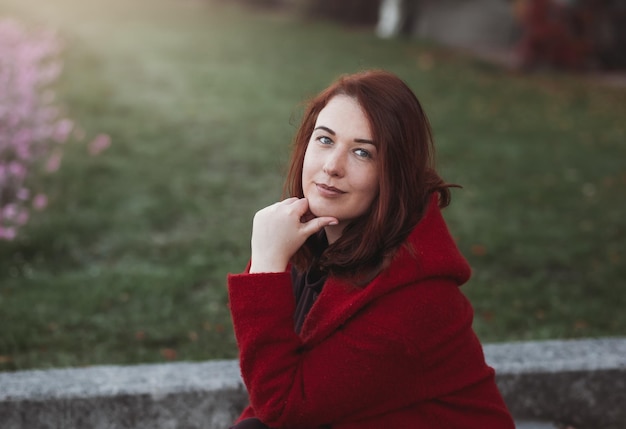 Elegant young woman in a burgundy casual coat in autumn Cute model walks in the park in golden autumn through colorful trees and fallen leaves Autumn walk colorful nature