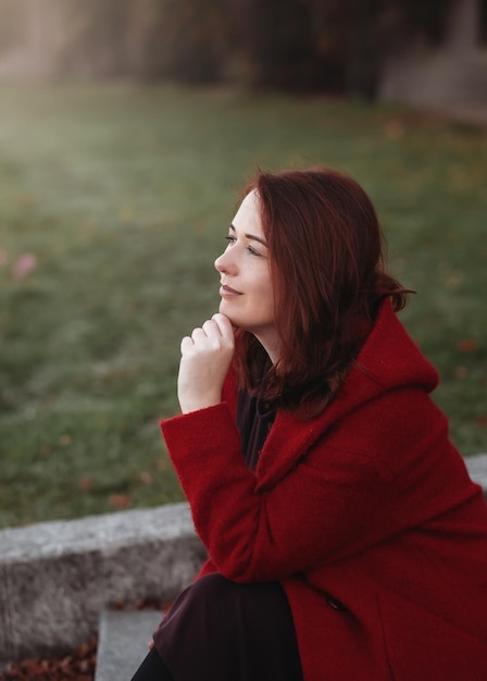 Elegant young woman in a burgundy casual coat in autumn Cute model walks in the park in golden autumn through colorful trees and fallen leaves Autumn walk colorful nature