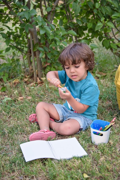 Elementary school age boys love to paint in parks Boys are drawing pictures as an outdoor hobby Concept of education outside of school