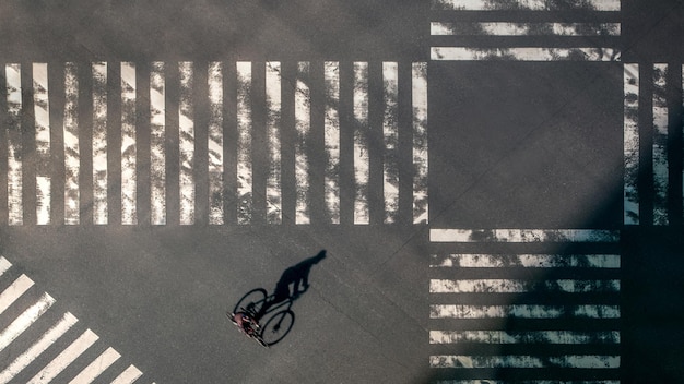 Elevated view over a biker man on pedestrian crossing in road intersection of Japan. Aerial view of bicycling at crosswalk. Asia downtown. Metropolitan Tokyo City