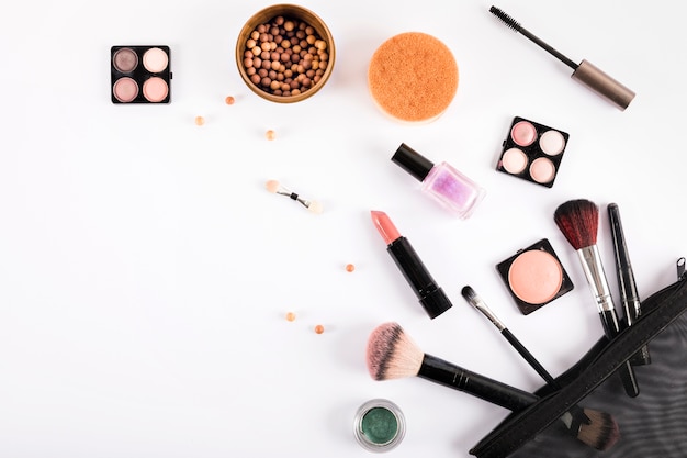 Elevated view of makeup brushes and cosmetics on white backdrop