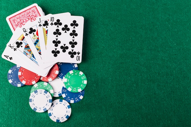 Elevated view of royal flush clubs and chips on green poker table