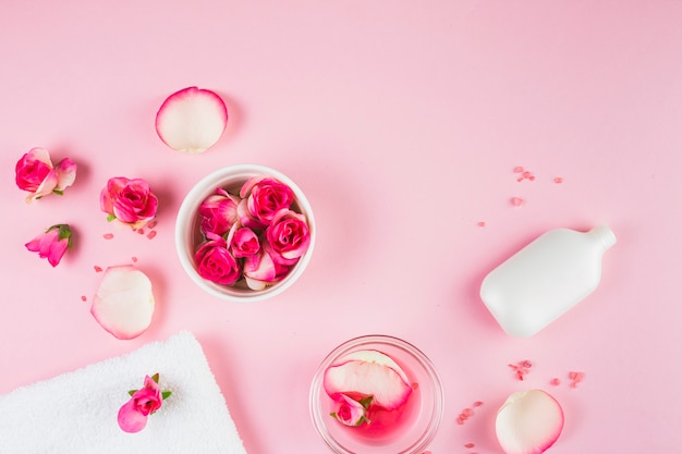 Elevated view of towel; flowers and bottle on pink background