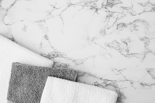 Elevated view of white and black towels on marble background