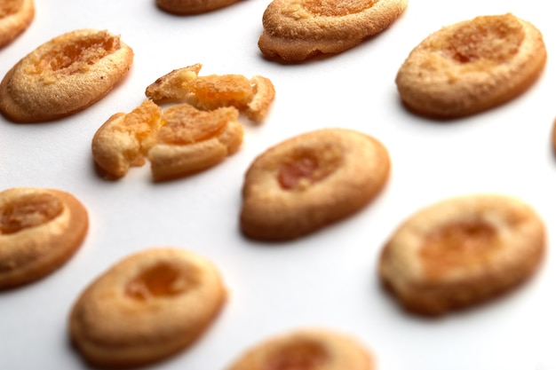 Eleven handmade cookies with apricot jam arranged in even rows from an angle.