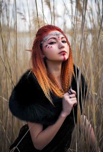 Elf women with fiery hair on nature. Beautiful young fantasy style girl. Cosplay character