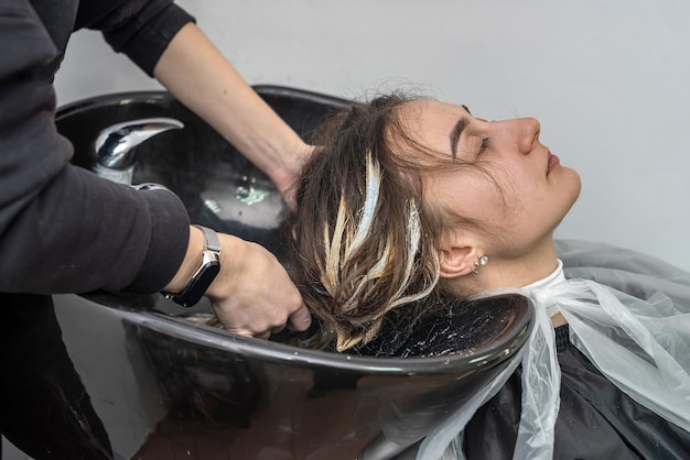 In an elite hairdresser's beautiful young woman washes her head in a special chair The concept of washing the head in a beauty salon