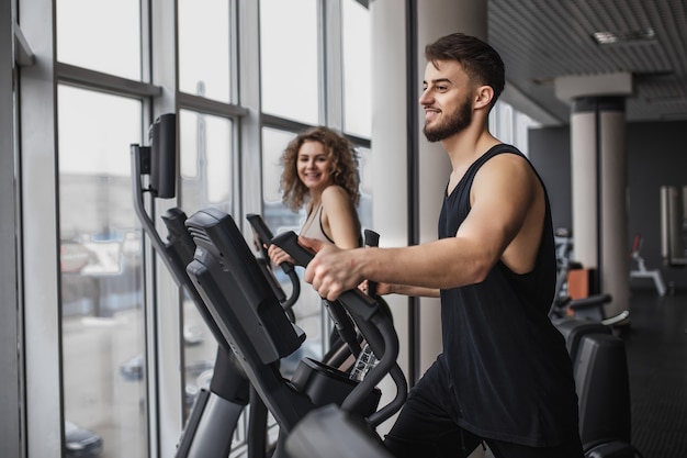 Elliptical walker trainer male and woman at the gym, doing exercise