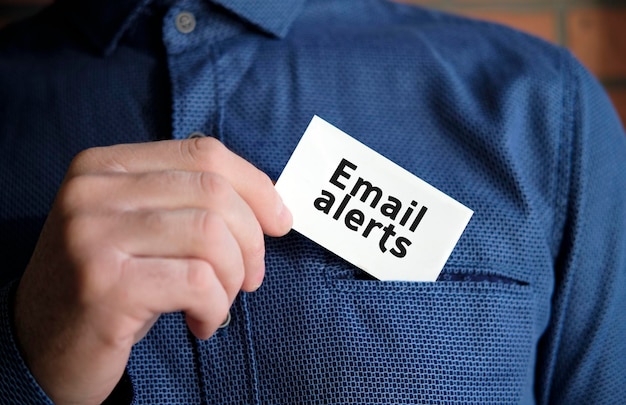 Email alerts text on a white sign in the hand of a man in shirt