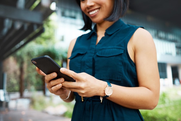 Email happy and business woman in the city of Singapore typing on a mobile app on a phone for work Corporate employee with a smile for communication and networking on smartphone in the morning