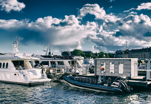 Embankment of Stockholm with yahts, water reflection, ships and deep blue sky with clouds - silver effect