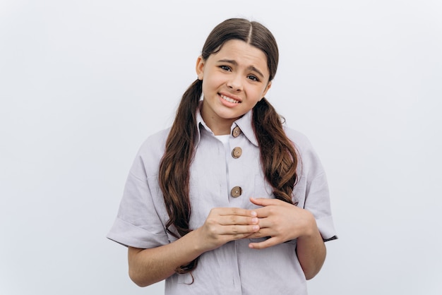 Embarrassed teenage girl with long, dark hair on a white background. The schoolgirl is very ashamed