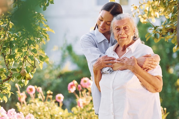 Embracing and smiling Young woman is with her senior mother is in the garden