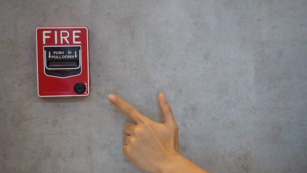 Emergency of Fire alarm or alert or bell warning equipment in red color with hand in the building for safety.