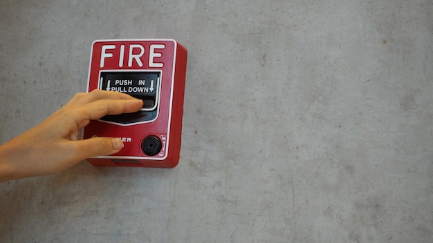 Emergency of Fire alarm or alert or bell warning equipment in red color with hand in the building for safety