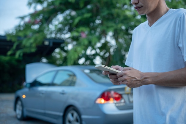 Emergency safety man is dialing a cell phone for an emergency number due to a car breakdown in the forest Maintenance of the car before the trip increases safety from accidents