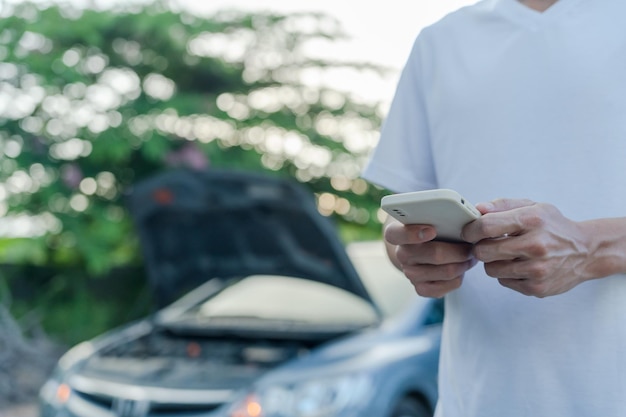 Emergency safety man is dialing a cell phone for an emergency number due to a car breakdown in the forest Maintenance of the car before the trip increases safety from accidents