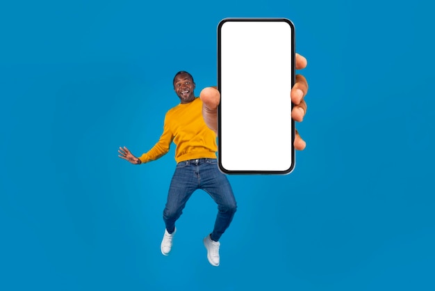 Emotional black man jumping up with cell phone mockup