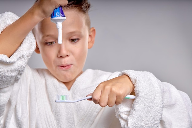 Emotional Child going to brush teeth Kid applying paste on tooth brush in bathrobe