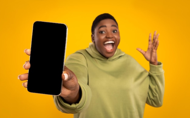 Emotional chubby african american woman holding smartphone with blank screen