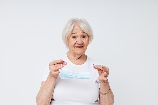 Emotional elderly woman medical mask in hand safety isolated background