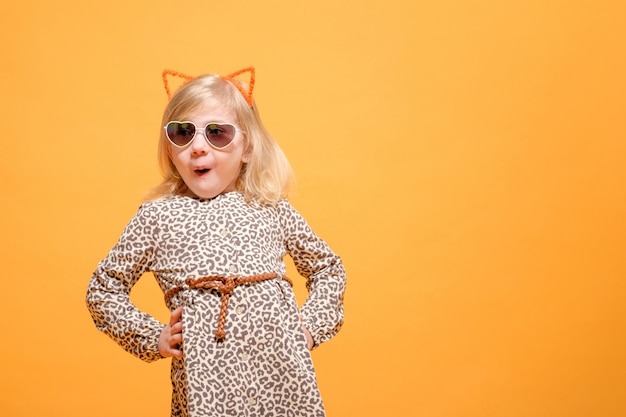 Emotional funny girl in leopard dress and glasses on yellow background posing