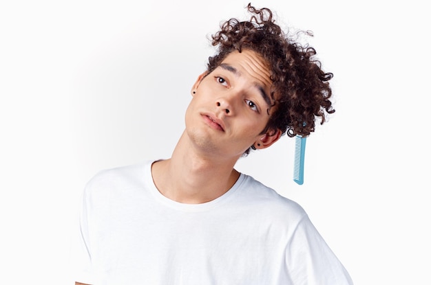 Emotional guy with curly hair combing hair light background