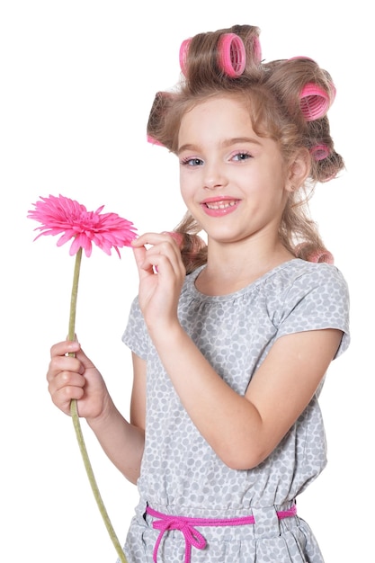 Emotional little pretty girl with hair curlers posing with flower isolated