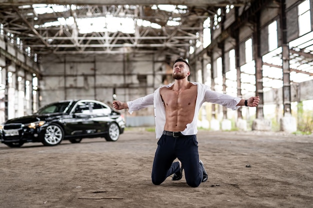 Emotional man in despair screams with emotional pain. Male in white unbuttoned shirt stands on knees with hands streched at sides. People`s emotions.