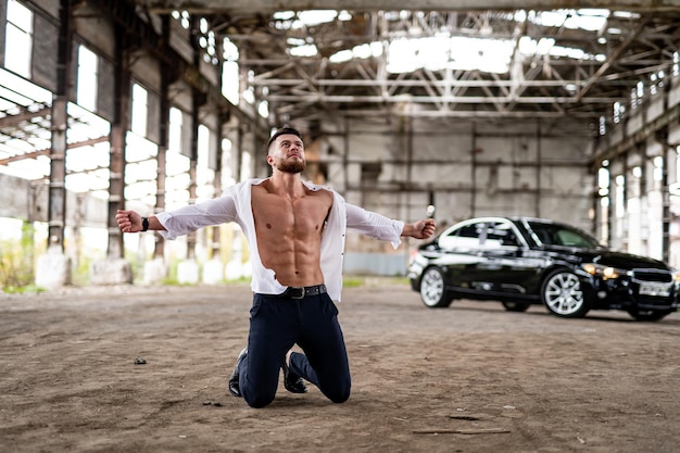 Emotional man in despair screams with emotional pain Male in white unbuttoned shirt stands on knees with hands streched at sides Peoples emotions