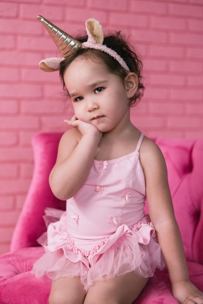 emotional portrait of little asian girl in a ballerina costume costumes on pink background