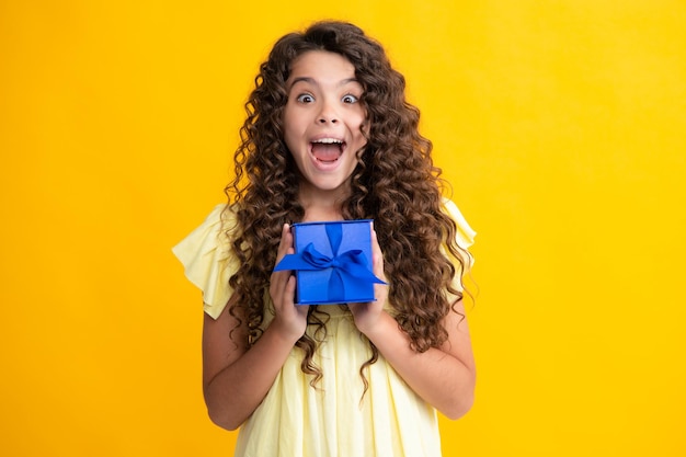 Emotional teenager child hold gift on birthday Funny kid girl holding gift boxes celebrating happy New Year or Christmas Excited teenager glad amazed and overjoyed emotions