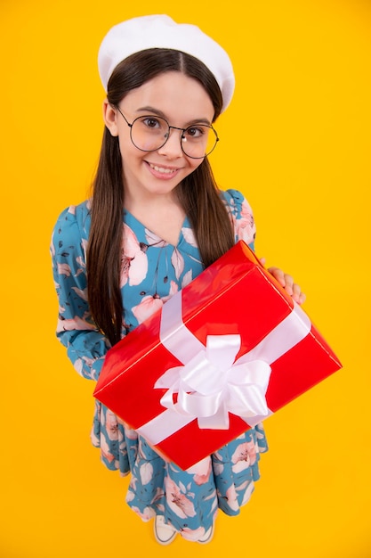 Emotional teenager child hold gift on birthday Funny kid girl holding gift boxes celebrating happy New Year or Christmas Happy teenager positive and smiling emotions