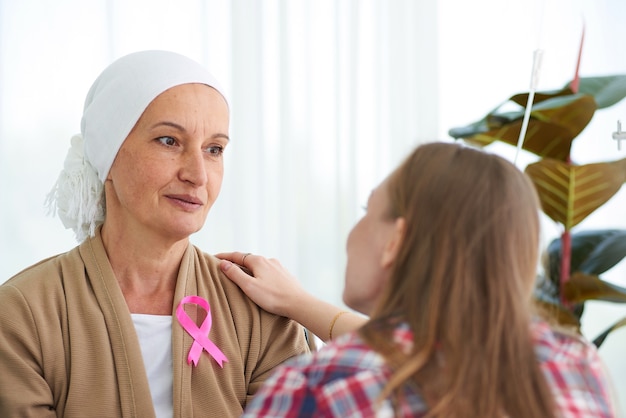 Emotional of young daughter white caucasian with hope and smile visiting and encourage to support her mother who fight with breast cancer hospital room,   Breast cancer awareness ribbon campaign.