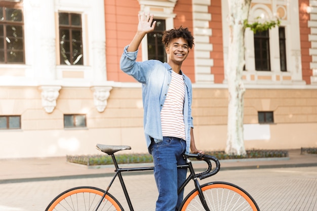 Emotional young guy on the street outdoors walking with bicycle