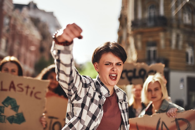 Emotional young woman screaming a slogan and leading a group of demonstrators on the road 