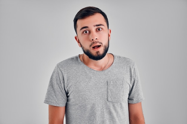 Emotions, advertising and people concept - surprised man in t-shirt over gray background