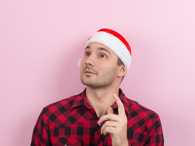 Emotions on the face, pensive, reflection, plan, idea. A man in a plaid rabbit and a Christmas red hat