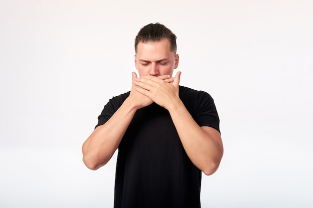 Emotions and feelings. Portrait of scared man with closed eyes covering his mouth with hands