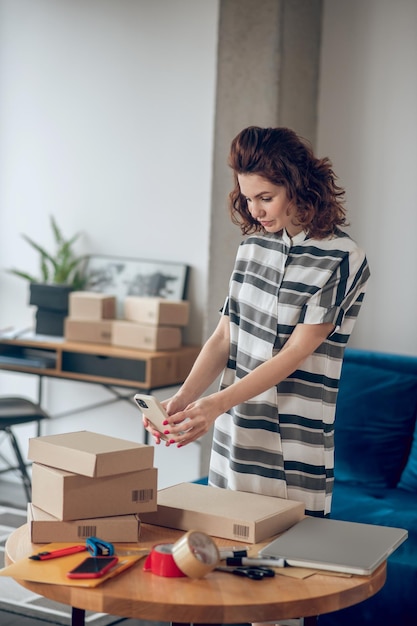 Employee aiming her smartphone camera at the cardboard box