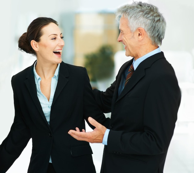 Employee laughing and meeting with boss in office for business in corporate company for strategy Woman happy and talking to leader of workplace in professional clothes for work or job for teamwork