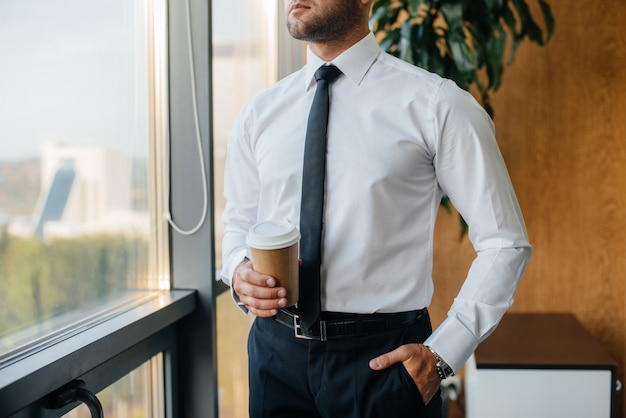 An employee in the office is standing near the window. Finance