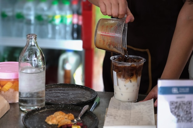 Employees are putting coffee into glasses to make latte for customers.