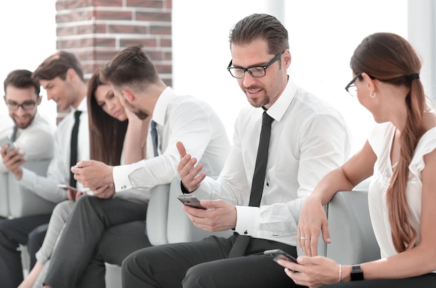 Employees of the company using their smartphones sitting in the office lobby