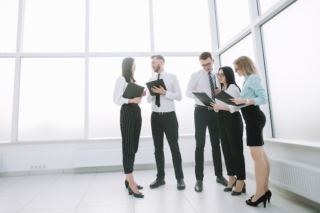 Employees discuss business documents standing in the office lobby