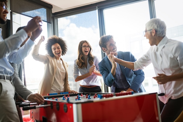 Employees playing table soccer indoor game in the office during break time to relieve stress from work